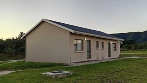 A single-story building with a flat roof, a small porch, and a grassy area in front.