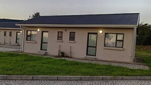 A row of modern, single-story buildings with a flat roof, numbered 10, set in a grassy area with a paved walkway.