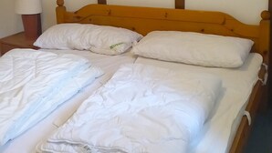 En enkeltseng med trægavl i et rum med skrå vægge.