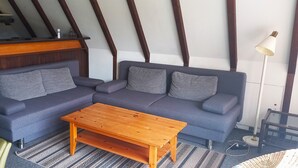 En moderne stue med en mørkeblå sofa, et træbord og et tæppe med et mønster.