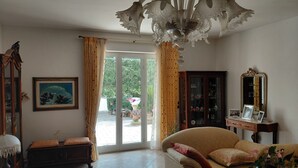 Una sala de estar con sofá, aparador, espejo y candelabro.