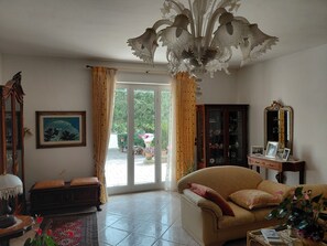 A living room with a sofa, a cabinet, a mirror, and a chandelier. - Villa with swimming pool surrounded by greenery (Muro Leccese)