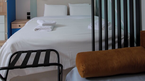 Une chambre d’hôtel comprenant un lit, une table de chevet, une chaise et une armoire.