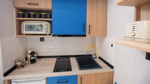 Une cuisine équipée d’un four à micro-ondes, d’un grille-pain, d’un évier et d’une cuisinière intégrée.