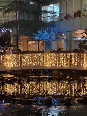 A building with a water feature, string lights, and a tree with blue lights.