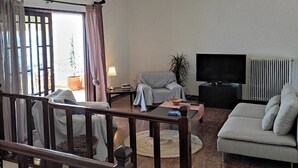 Ein Wohnzimmer mit einer Couch, einem Fernseher und einer Treppe.
