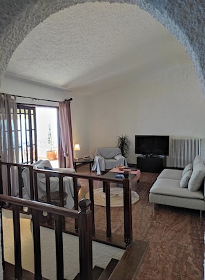 Ein Wohnzimmer mit einer Couch, einem Fernseher und einer Treppe.