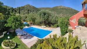 Ein Pool mit einer Terrasse, einem Esstisch und einer Treppe, die zu einem Balkon führt.