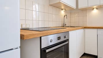 A kitchen with white cabinets, a wooden countertop, a stainless steel range hood, and a built-in oven.