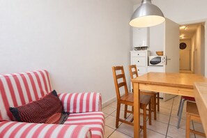 A cozy room with a striped sofa, wooden dining table, and chairs. A modern pendant light hangs above the table. - New Leonrod  · Big groups Oktoberfest (MÃ¼nchen)