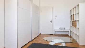 A modern interior with a glass-top table, a bench, and white shelving with baskets.