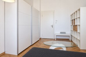 A modern interior with a glass-top table, a bench, and white shelving with baskets. - New Leonrod  · Big groups Oktoberfest (MÃ¼nchen)