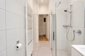Une salle de bain moderne avec une douche à parois de verre, un porte-rouleau de papier toilette et un porte-serviettes.