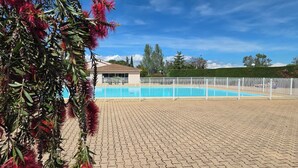 A swimming pool with a white fence, a building in the background, and a hedge. - The Golf Studio. Swimming pool, close to beach, walks, golf course, shops and restaurants. (Mandelieu-la-Napoule)
