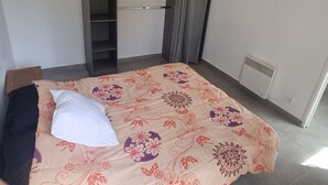 Ett sovrum med en säng, en garderob, en klädstång och ett element.