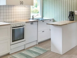 A modern kitchen with white cabinetry, a built-in oven, a dishwasher, and a coffee maker on the countertop.