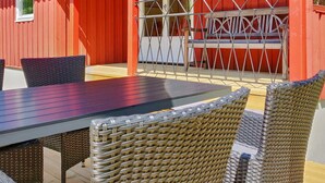 Edifício vermelho com um pátio com mesa e cadeiras de vime.