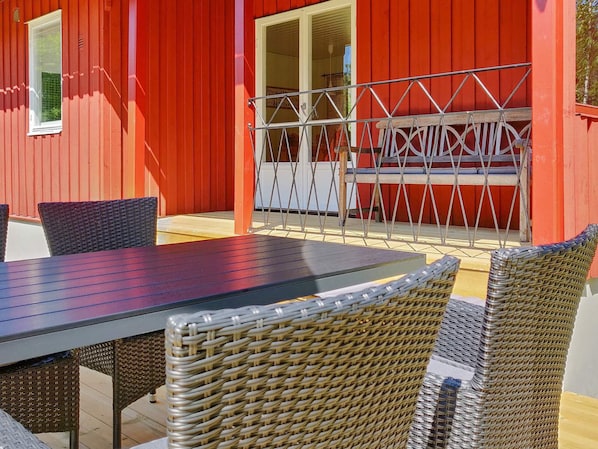A red building with a patio area featuring a table and wicker chairs.