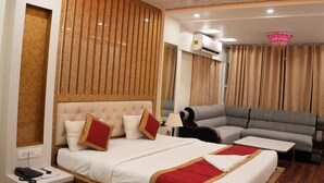 A bedroom with a bed, bedside table, nightstand, and a sofa. - Aradhaya Heritage Hotel (Bodh Gaya)