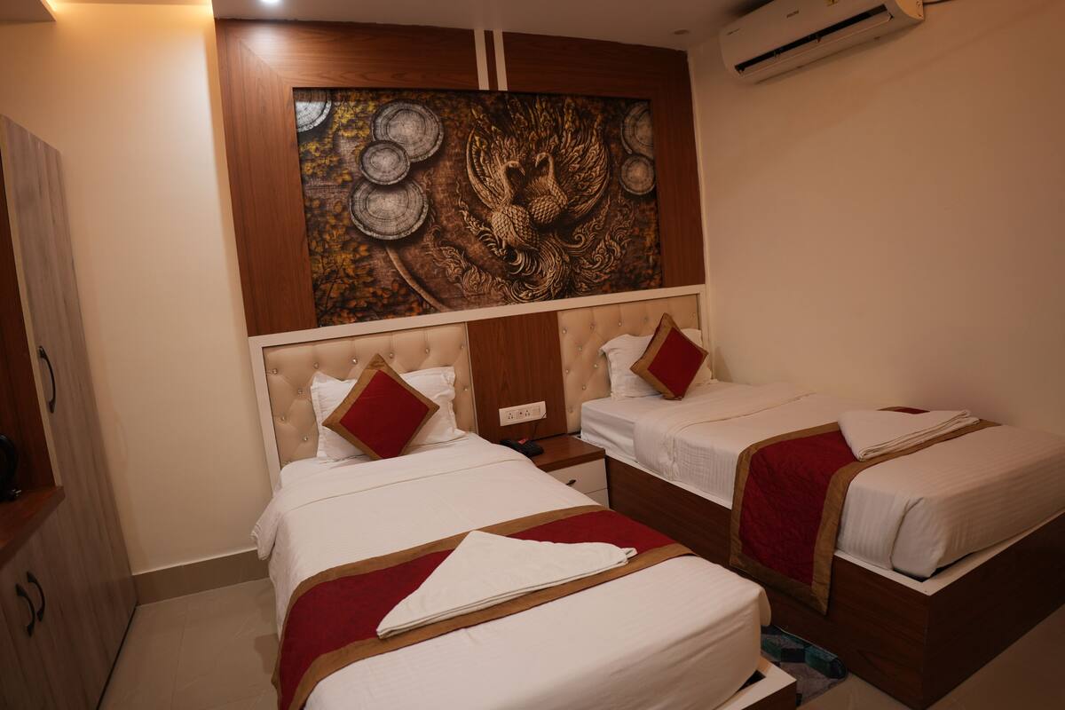 Habitación de hotel con dos camas, cabecera de madera, tapiz en la pared y aire acondicionado en el techo.