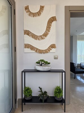 Ein modernes Interieur mit einem schlichten Konsolentisch, einem Bonsai-Baum und Wanddekoration.