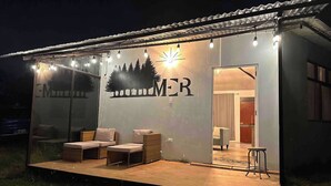 Une petite construction d’un seul étage, dotée d’une façade en verre, d’un logo représentant des arbres et du mot « MER », ainsi que d’un patio aménagé avec des sièges.