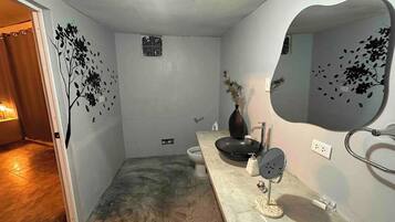 Une salle de bain avec un lavabo, un miroir et un motif décoratif représentant un arbre appliqué sur le mur.