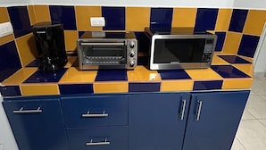 Eine Küche mit Mikrowelle, Toaster und Kaffeemaschine auf einer blau-gelben Fliesenarbeitsplatte.