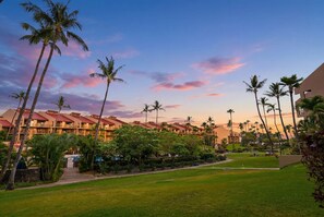 A resort with multiple-story buildings, palm trees, and a well-maintained lawn. - Maui Bliss Garden Lanai, Dual AC, Beach, Pool, Gym (Kihei)