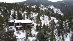 Een chalet met een tweelaags gebouw, omringd door met sneeuw bedekte bomen en bergen.