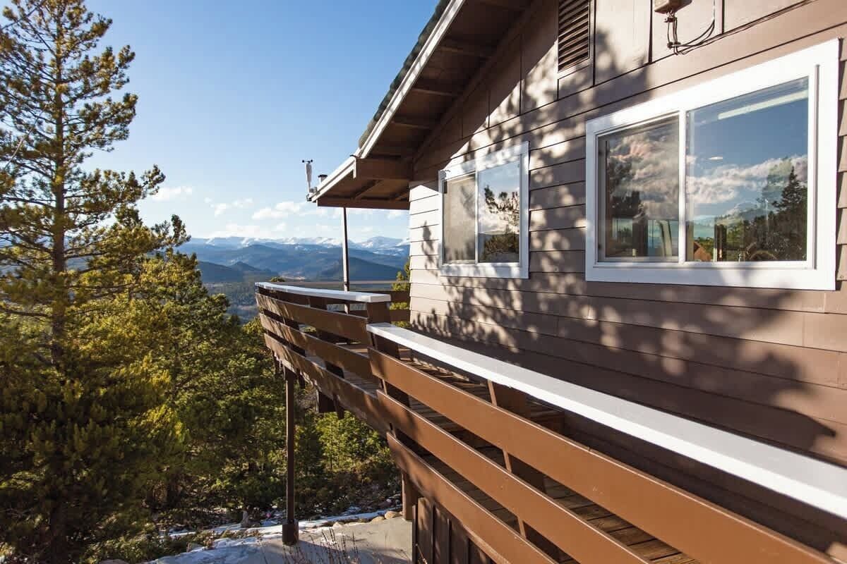 Una cabaña de madera con balcón con vistas a un paisaje montañoso.
