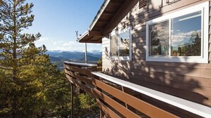 Een houten hutje met een balkon met uitzicht op een bergachtig landschap.
