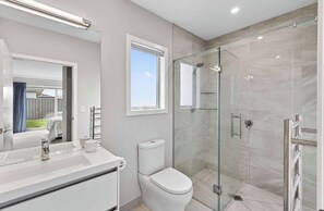 Ein modernes Badezimmer mit einer Duschkabine, einer Toilette und einem Waschbecken mit Spiegel.