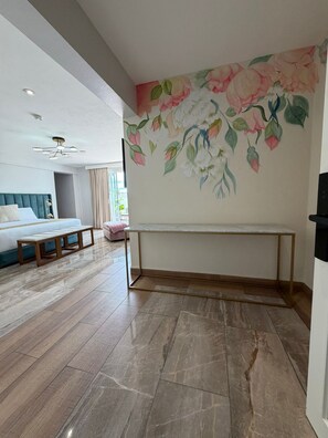 Et moderne hotelværelse med en stor seng, en bænk, et skrivebord og et blomstermotiv på væggen.