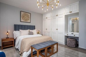 Un dormitorio con cama, mesitas de noche, un banco, un armario y un espejo.