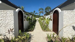 A pathway leading to a building with arched doors and a stone exterior. - Kairos boutique sports hotel (Selong Belanak)