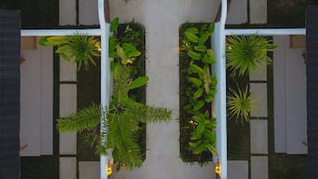 Un espacio exterior simétrico con un camino central bordeado por jardineras y zonas de estar.