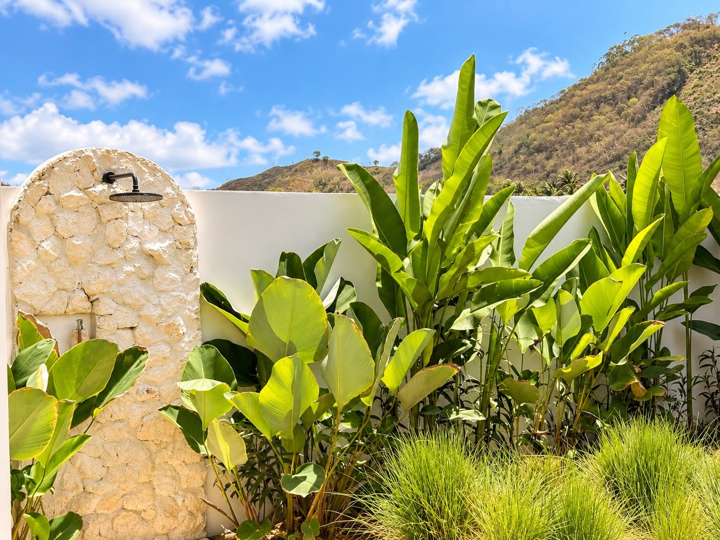 A stone wall with a water feature and lush green foliage.