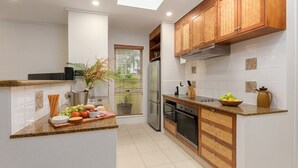 Una cocina moderna con horno empotrado, refrigerador, gabinetes de madera y una encimera con diversos alimentos.