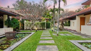 Un jardín bien cuidado con un camino de piedra que lleva a un edificio con tejado de baldosas.