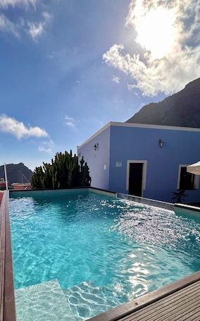 A clear blue pool with a wooden deck, a cactus garden, and a mountain in the background.. Standard room with breakfast - Casa Regina Tenerife with swimming pool