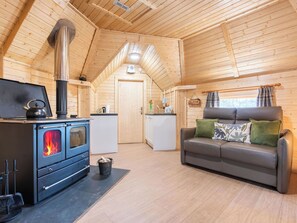 Ein gemütliches Blockhaus-Interieur mit Kaminofen, einer Couch und einer Küchenzeile.