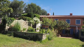 Ein zweistöckiges Haus mit Steinmauer, Garten und einer Terrassenfläche.