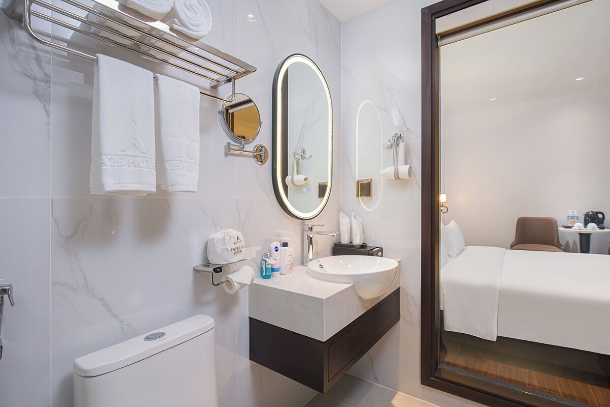 A modern hotel bathroom with a toilet, sink, and mirror.