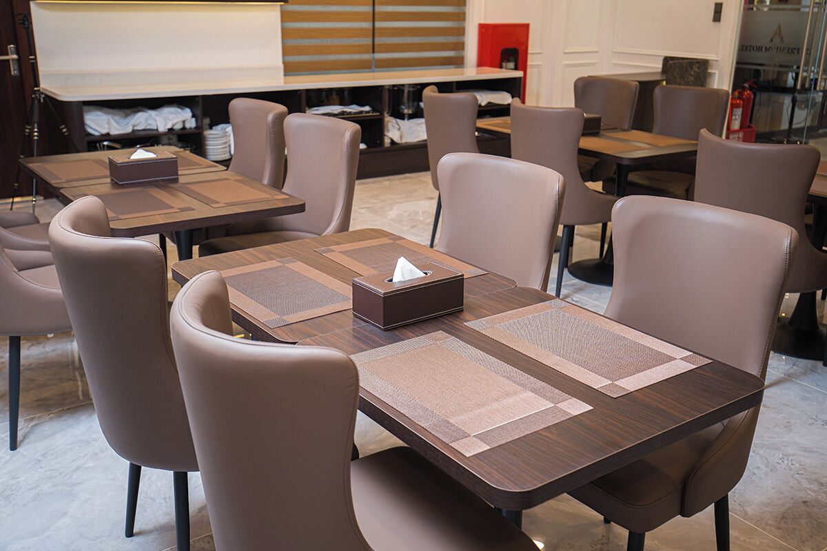 A hotel dining area with multiple tables and chairs, a fire extinguisher, and a whiteboard in the background.