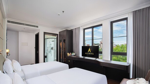 Habitación de hotel con dos camas, un escritorio, un televisor y una ventana con vistas.