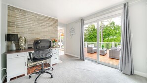 A room with a desk, chair, and a view of an outdoor deck. - Luxury & Private 6BR Single House • Summer Retreat w/ Parking & Pet-Friendly 35 (Randolph)