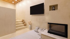 Quarto moderno com televisão, lareira e escada.