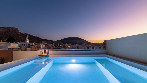 Piscina no terraço com vista para a cidade e montanha ao entardecer.