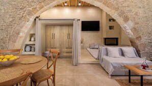 Um quarto aconchegante com arco de pedra, móveis de madeira, um sofá e uma televisão.